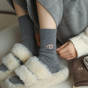 Close-up of wool socks with small dog embroidery and colorful speckled knit details
