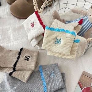 Detail of knit socks with bow embroidery and ruffled edges in vintage beige and brown