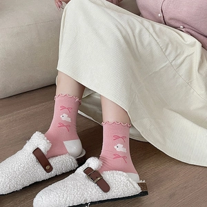 Detail of pink crew socks featuring frilly cuffs and cute white cloud patterns