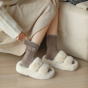 Détail de chaussettes en laine avec broderie et pantoufles en fausse fourrure crème