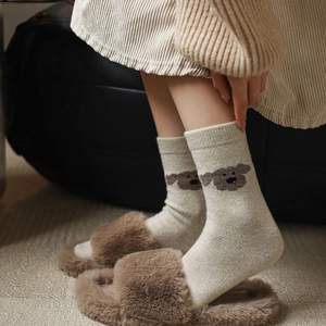 Détail de chaussettes en tricot couleur avoine avec motif chien et pantoufles