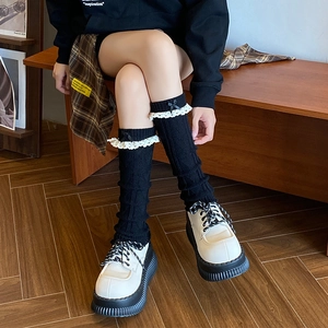 Jambières en tricot noir avec dentelle blanche et nœud papillon portées par un mannequin