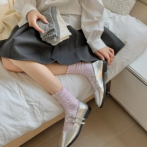 Nahaufnahme süßer floraler Spitzensocken in Grau, Weiß und Lila mit Mary Jane Schuhen