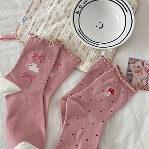 Detail of pink cotton socks with rabbit embroidery, bow prints, and ruffled cuffs
