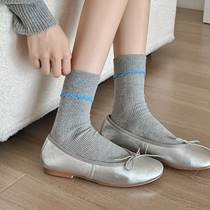 Detail of grey ribbed knit socks featuring blue bow embroidery and wavy edge trim