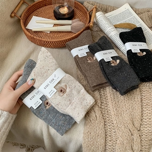 Close-up of wool socks with cute animal embroidery and thick speckled knit texture