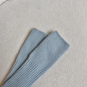 Détail de jambières en tricot bleu gris montrant les poignets côtelés et la maille