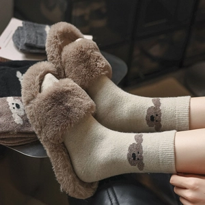 Gros plan de chaussettes en tricot beige avec motif d'ours et pantoufles en peluche marron