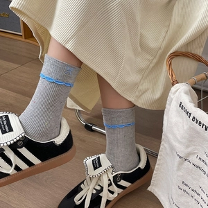 Detailed view of grey lace socks with blue bow embroidery and wavy trim on feet