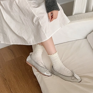 Nahaufnahme silberner Ballerinas mit Schleife und weißer Spitzen-Jacquard-Socken