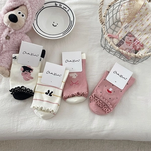 Close-up of cute socks with ruffle cuffs, bow embroidery, and teddy bear motifs