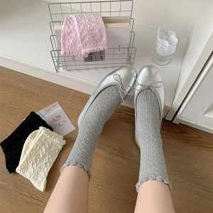Nahaufnahme von grauen Spitzen-Rüschensocken mit glänzenden silbernen Ballerinas