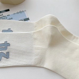 Detailed close-up of ribbed cotton socks with minimalist blue letter embroidery