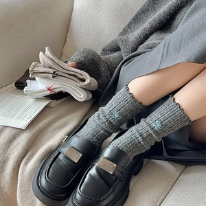 Detail of wool socks featuring ruffled edges and delicate bow embroidery accents
