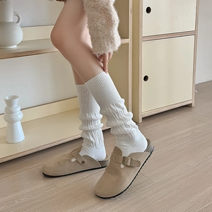 Detail of khaki suede mule with metal buckle worn over cozy white slouch socks