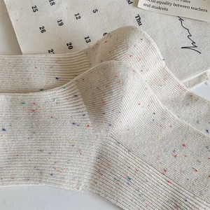 Close-up detail of cream cotton ribbed socks featuring colorful confetti knit pattern