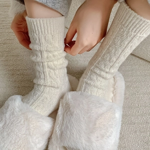 Thick cream cable knit wool socks for winter warmth, styled with white plush slippers