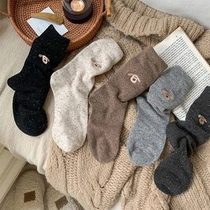 Close-up of five pairs of thick wool socks featuring cute dog embroidery and flecked yarn