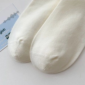Detailed close-up of cream cotton knit crew socks showing fine toe stitching and texture
