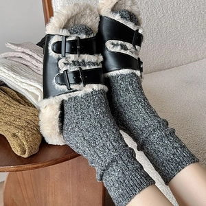 Close-up of thick grey cable knit leg warmers paired with plush black buckled slippers