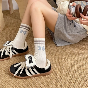 Detail of retro sneakers and white knit socks with stripe and number 24 embroidery