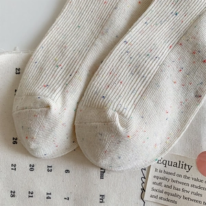 Detail of oat knitting socks with colorful polka dots and ribbed texture on rustic fabric