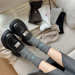 Detail of wool blend socks with bow embroidery and ruffled cuffs with leather loafers