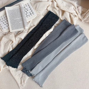 Détail de jambières en tricot côtelé noir doré et gris avec des bords festonnés délicats