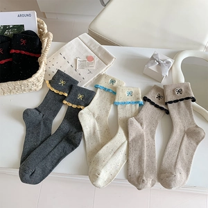 Detailed macro of ballet-style socks with bow embroidery and scalloped edges
