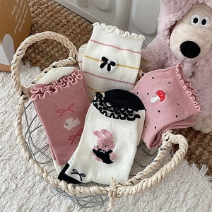 Close-up of four pairs of bow embroidery socks with wavy lettuce edges in a woven basket
