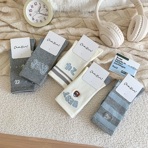 Close-up of five pairs of Japanese cartoon embroidery crew socks with various color stripes