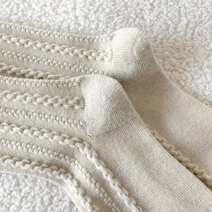 Détail de la chaussette en laine beige montrant la texture en maille torsadée chaude