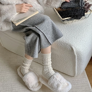 Detail view of white cable knit wool socks and plush slippers for cozy winter home wear