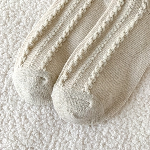 Gros plan détaillé de chaussettes en laine crème avec motif torsadé et texture douce