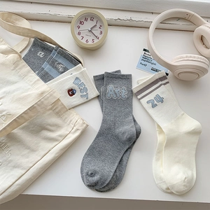 Detail of embroidered crew socks with stripes and letters in minimalist college style