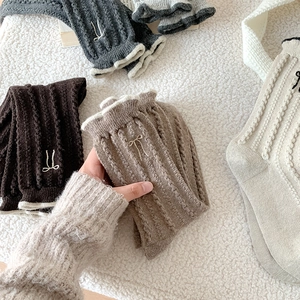 Détail de chaussettes en laine tricotée avec broderie nœud et bordure à volants