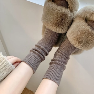 Detail of cable knit wool socks in mauve paired with cozy plush faux fur slippers