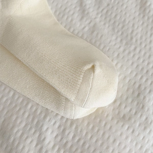 Dettaglio ravvicinato di calze a maglia a coste color crema con cuciture sulle dita lisce