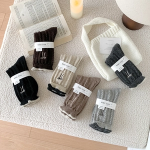 Détail de chaussettes en laine avec torsades et broderie nœud en plusieurs couleurs