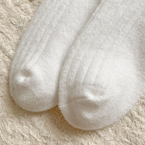 Close-up of white wool socks showing vertical knit texture and soft fuzzy material detail
