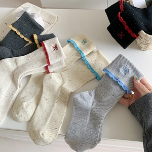 Close-up of ballet style bow embroidery and wavy edge on cotton knit crew socks
