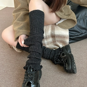 Gros plan de jambières en tricot noir avec fils pailletés et bordures à volants