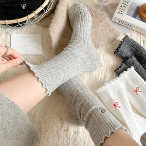 Detail of wool socks showing ribbed texture, lettuce edge cuffs and bow embroidery
