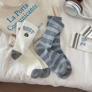 Detail of striped cotton socks with cute bear embroidery and ribbed texture on white fabric