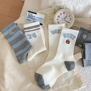 Close-up of cotton socks featuring cartoon bear embroidery and blue striped athletic patterns