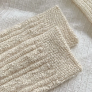 Detail of cream cable knit wool socks featuring shimmering silver thread and ribbed texture
