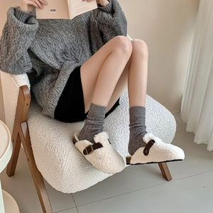 Detail of cream sherpa mule clogs with brown leather straps and grey knit wool socks
