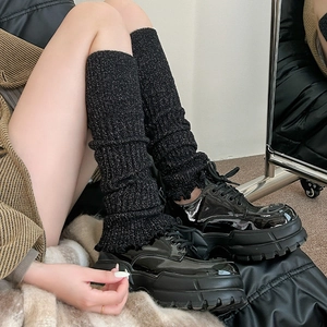 Détail de jambières noires tricotées scintillantes portées avec des chaussures compensées