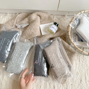 Detail of wool socks with bow embroidery and scalloped edges in organized gift packaging