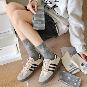 Close-up of rib-knit cotton socks featuring blue stripes and minimalist letter embroidery